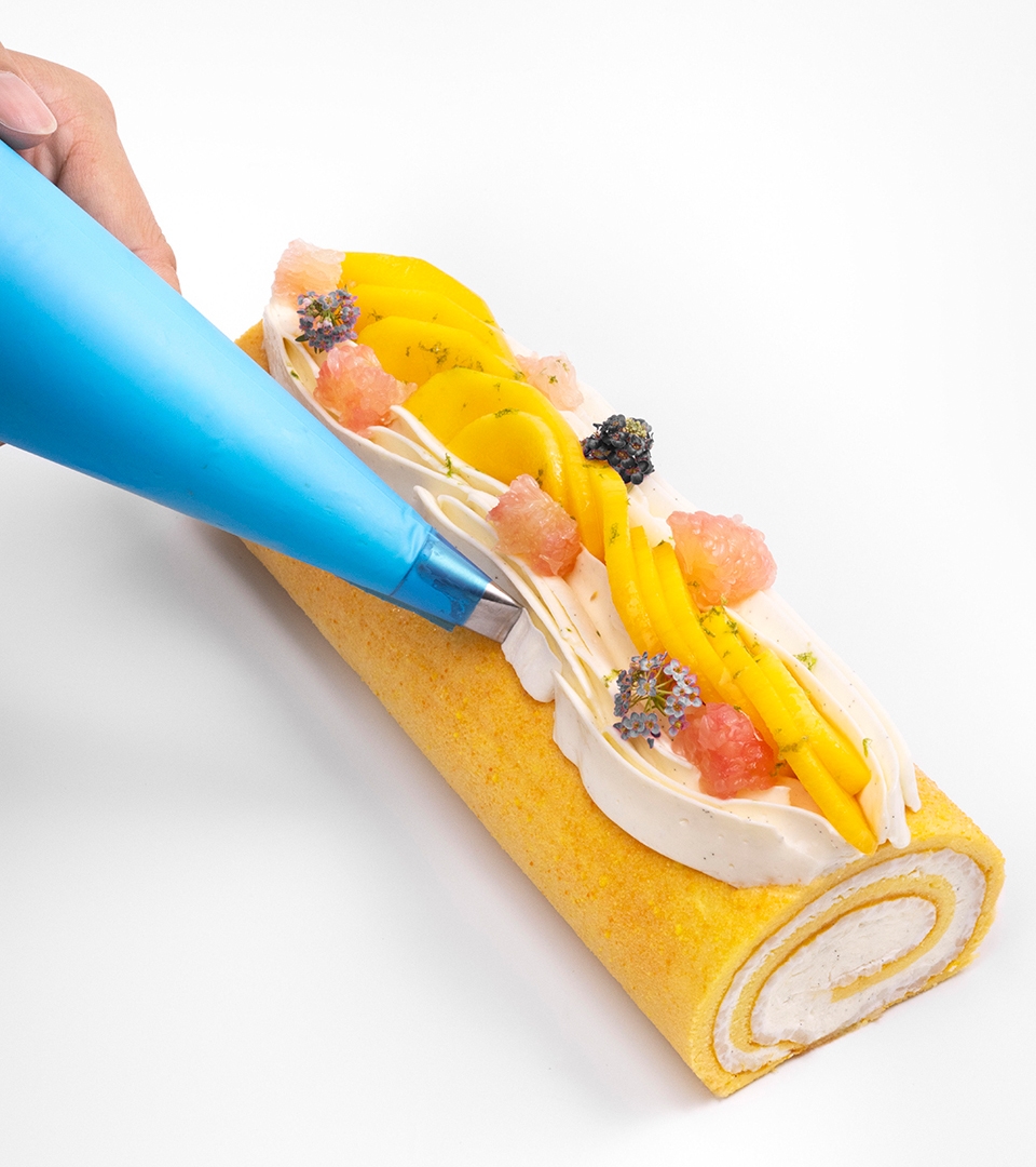 Szef Otto Tay wyciska bitą śmietankę na ryżową roladę mango w stylu szwajcarskiej rolady