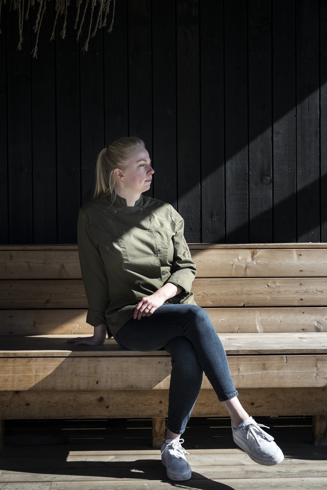 Marie Koopman zittend op een bank van houten pallets.