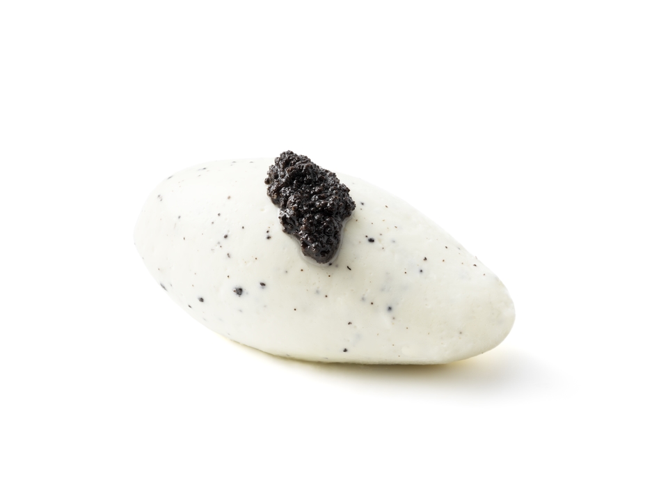 A white quenelle topped with a small spoonful of black caviar