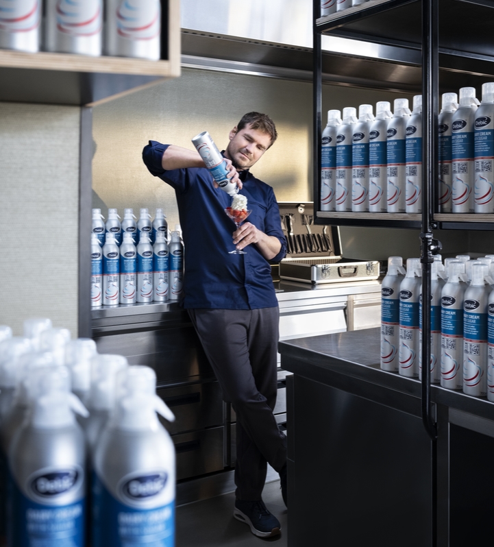 A man using Debic Spraycan while surrounded by hundreds of Spraycans on shelves.