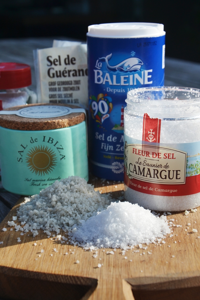 Assortiment de sels gastronomiques, dont la fleur de sel, présentés en pots et en tas.