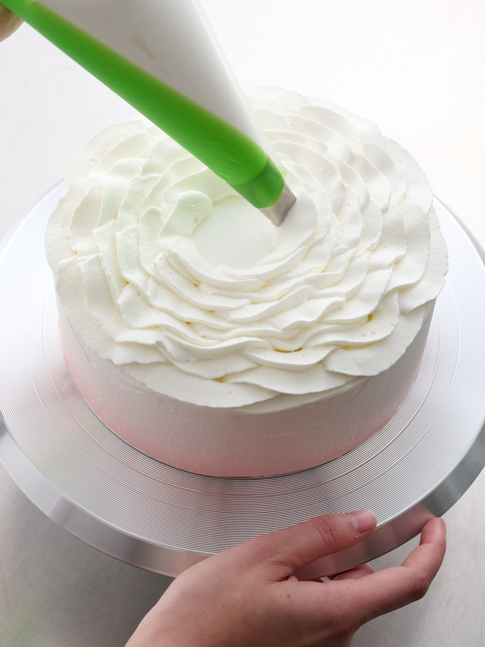 Mains décorant un gâteau avec un glaçage blanc à la poche