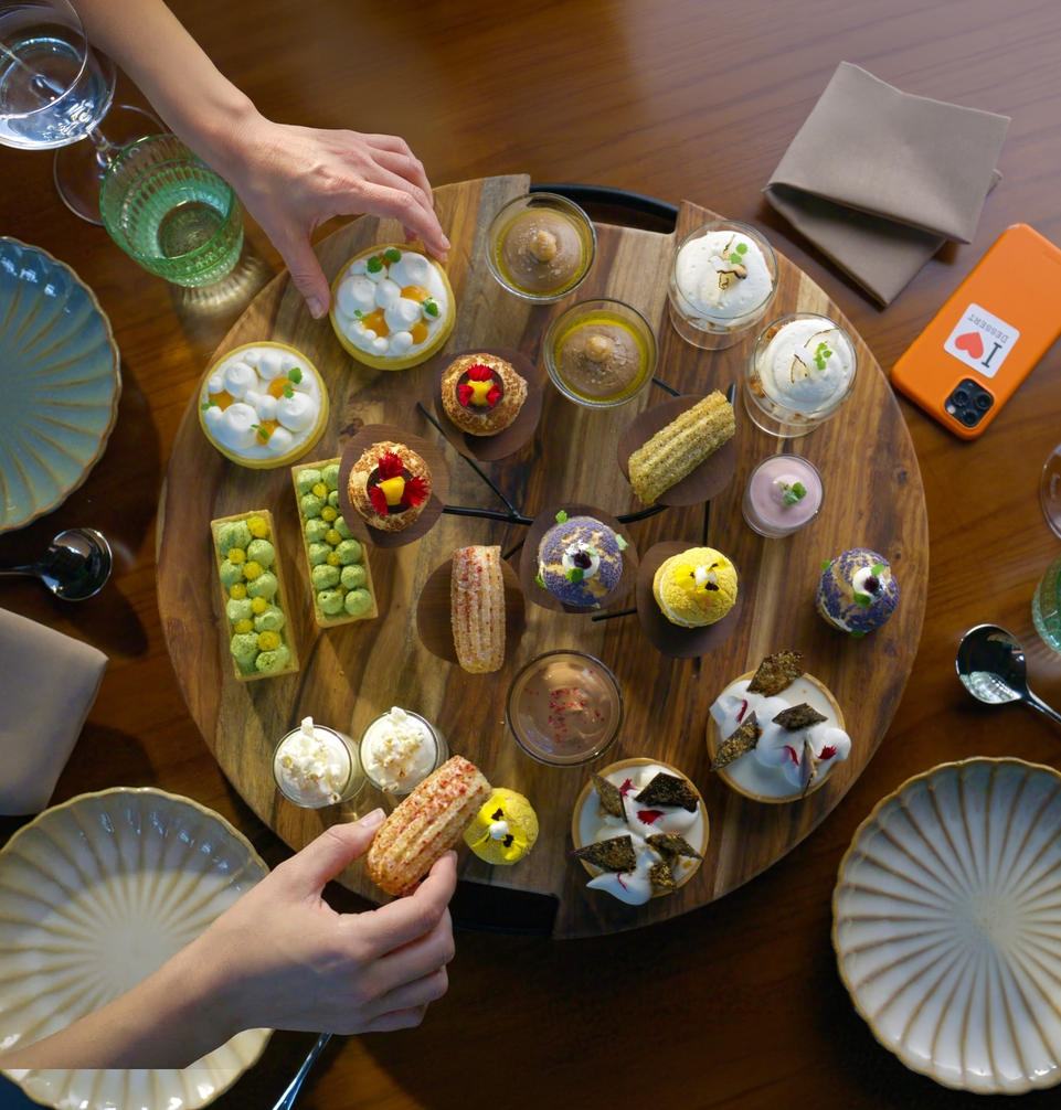 Overhead view of hands selecting dessert tapas from a shared platter.