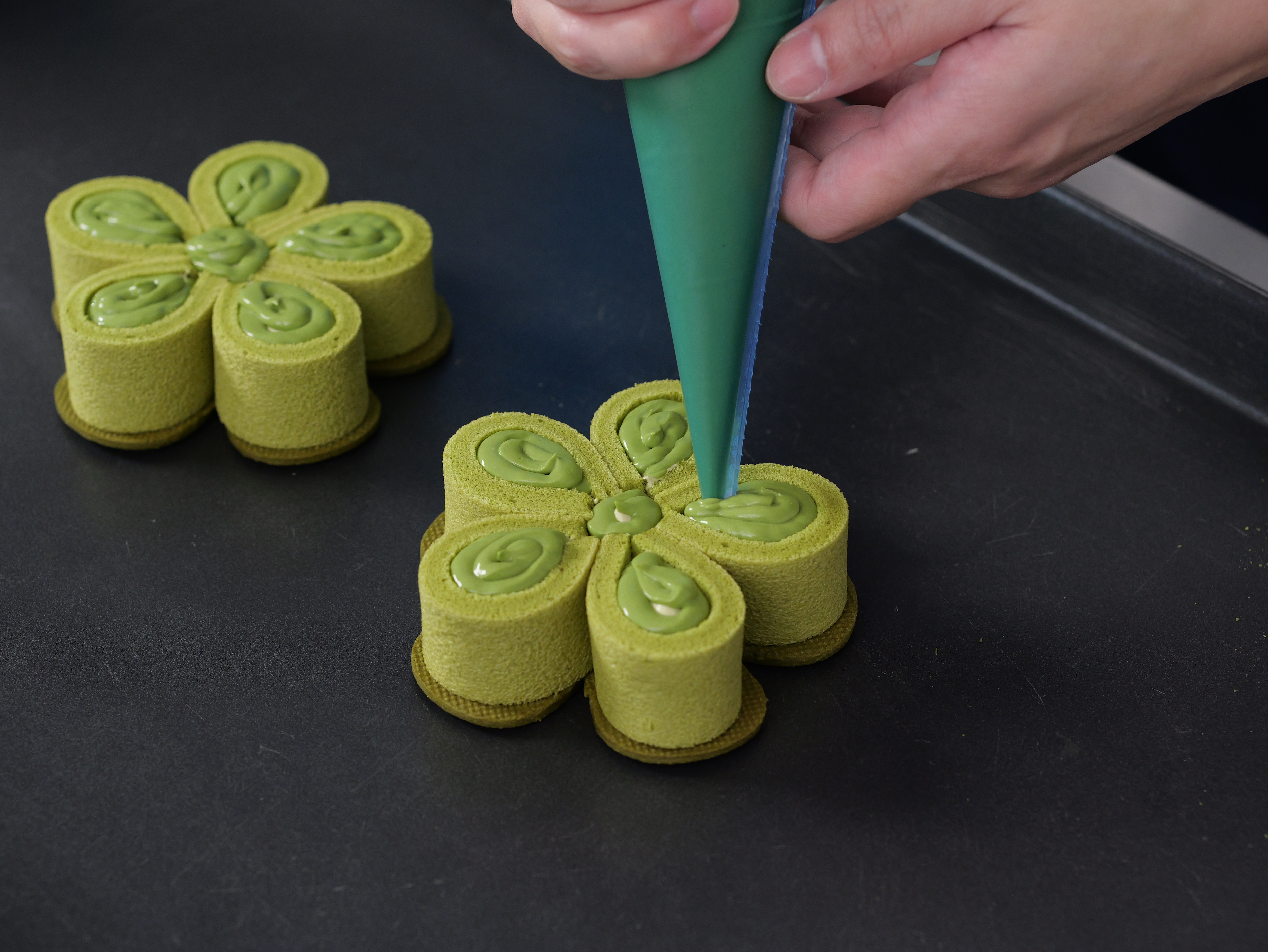 Chef Loi pipes whipped cream onto a Matcha Flowers.