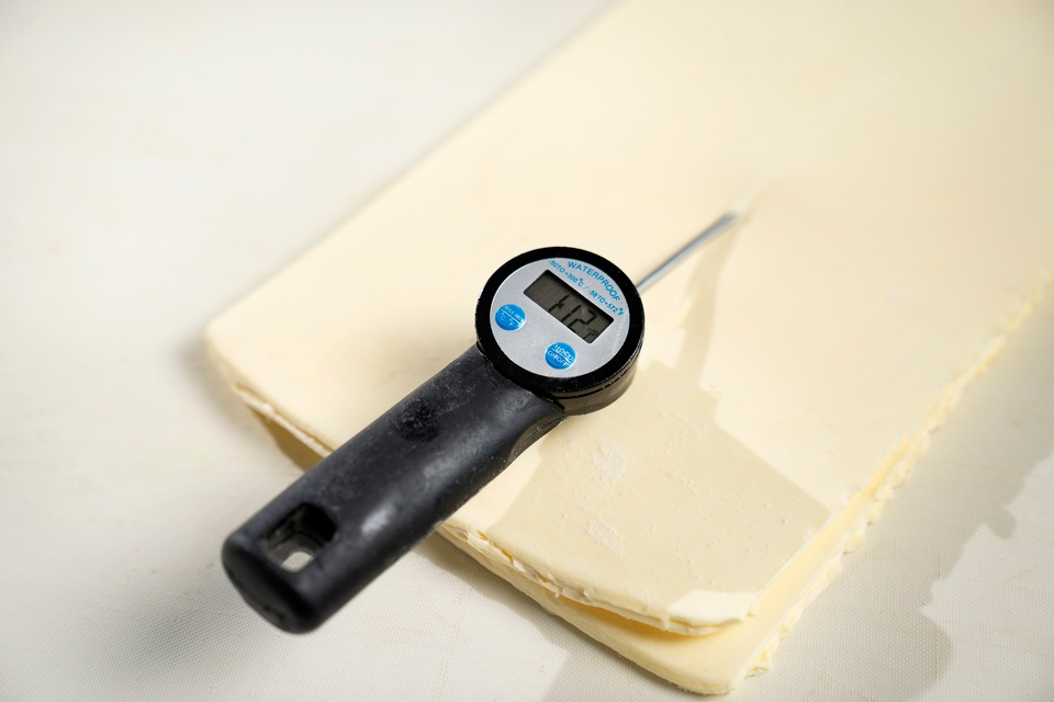 Termometro digitale appoggiato su una sfoglia di pasta sfoglia.