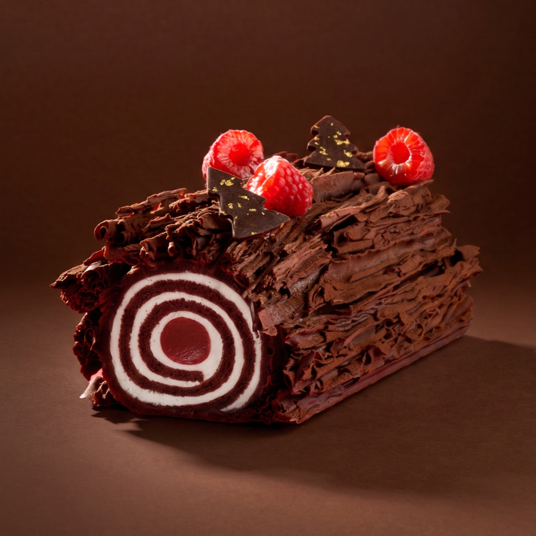 Chocolade kerststronken versierd met verse frambozen en chocoladeschaafsel.