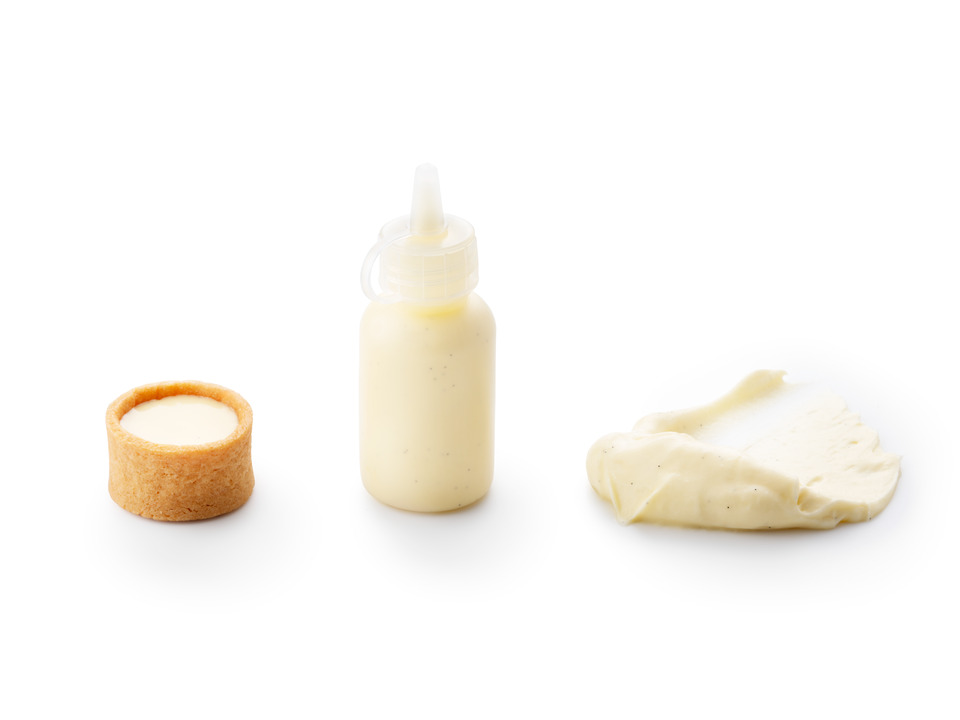 Three applications of Debic Crème Brûlée Bourbon on a white background: a tartlet filled with creamy custard, a squeeze bottle of dessert sauce, and a smooth crème spread.