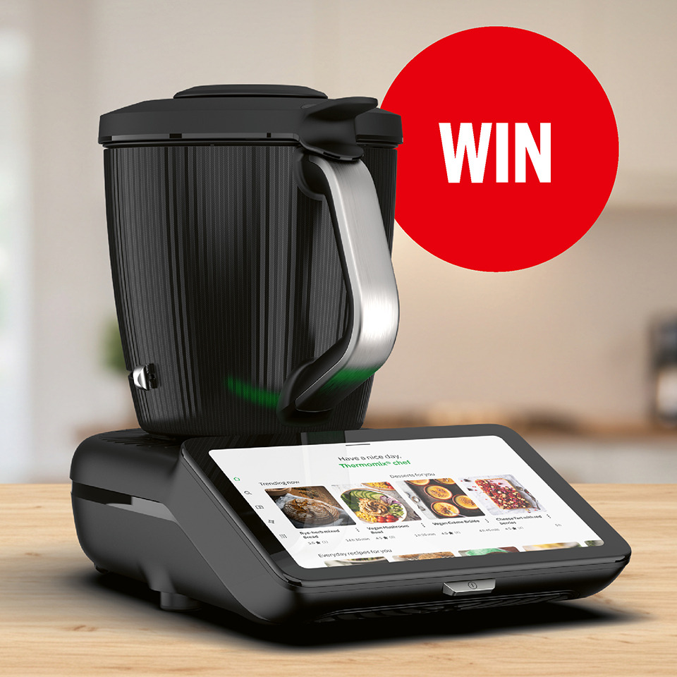 Een moderne zwarte Thermomix keukenmachine met een digitaal display waarop recepten staan. Rechtsboven staat een opvallende rode cirkel met de tekst "WIN".