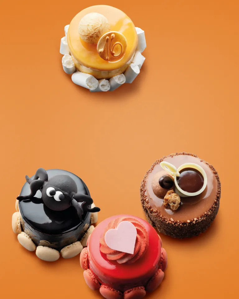 Four decorated mini cakes on an orange background