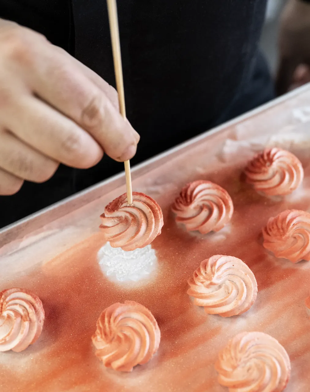 Hand painting small swirled cream decorations with red color