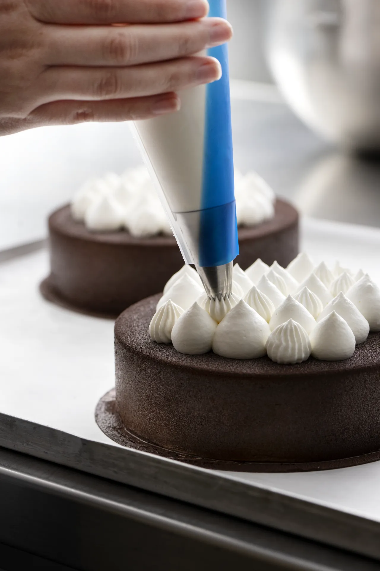 Piping white decoration on a chocolate cake